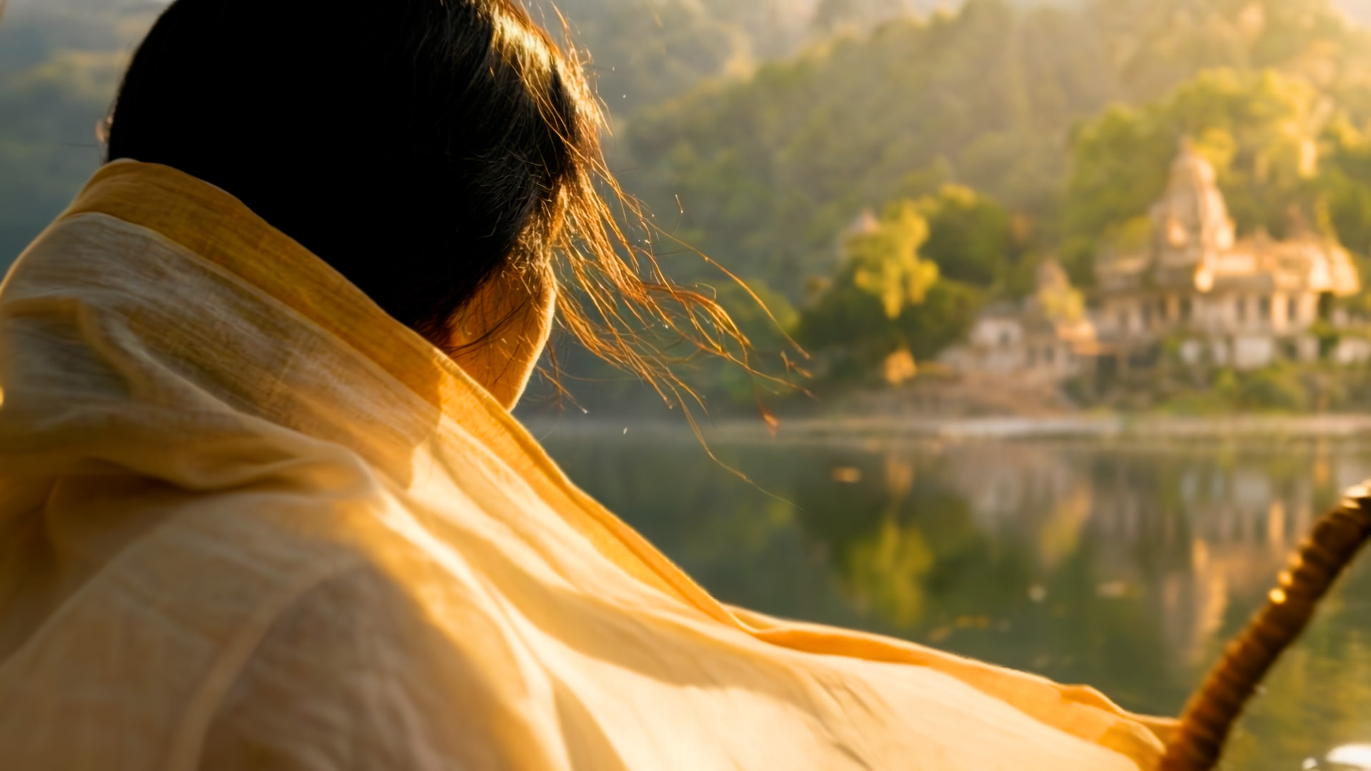 Meera looking across the river toward a golden temple at sunrise