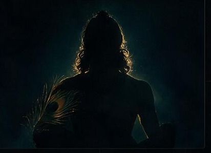 Silhouette of Krishna holding a peacock feather in low divine light